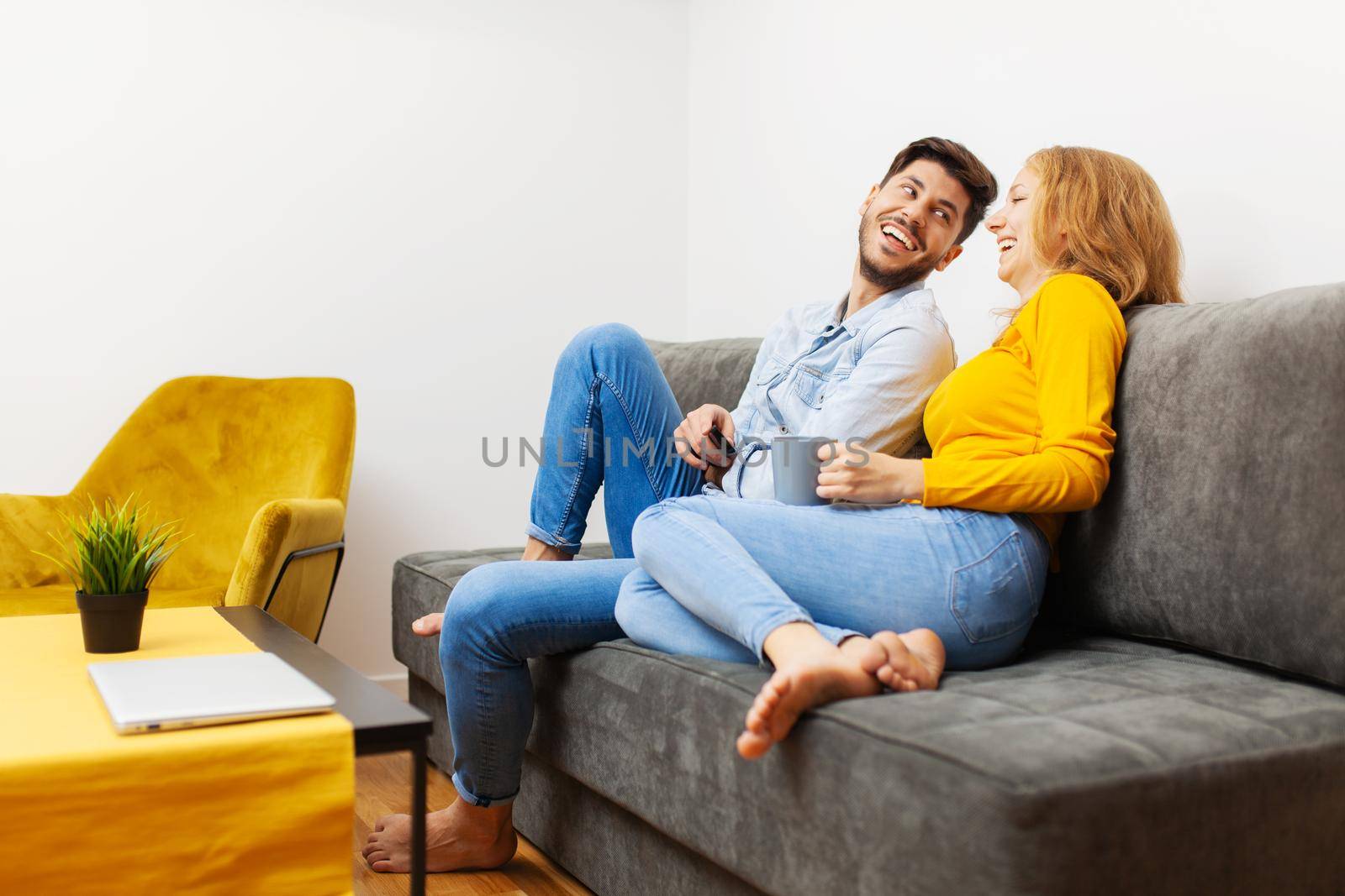 couple in love on a sofa watching tv and smiling