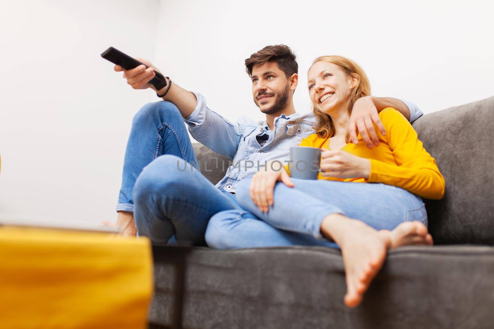 couple in love on a sofa watching tv and smiling