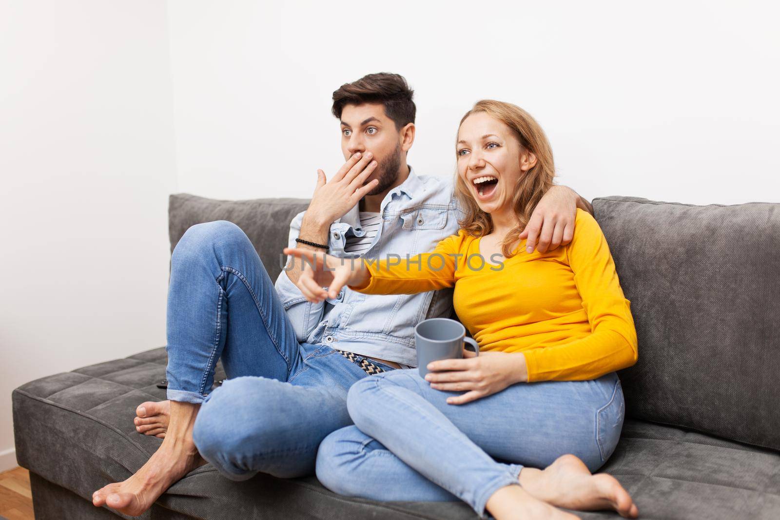 couple in love on a sofa watching tv and smiling by kokimk