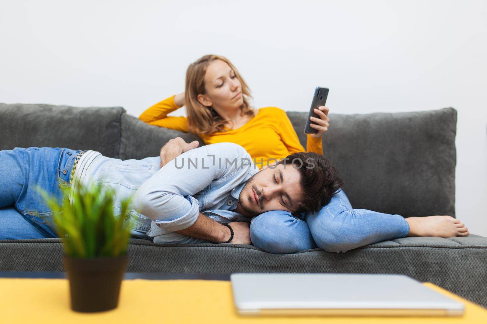 boy naps on girlfriend's lap while she looks at smart phone by kokimk