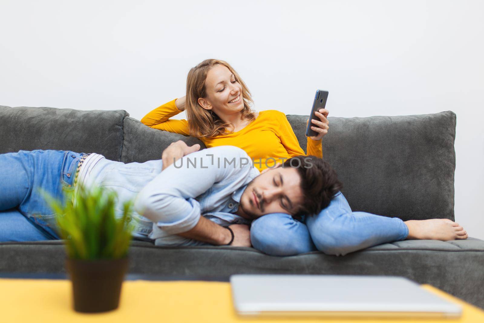 boy naps on girlfriend's lap while she looks at smart phone by kokimk