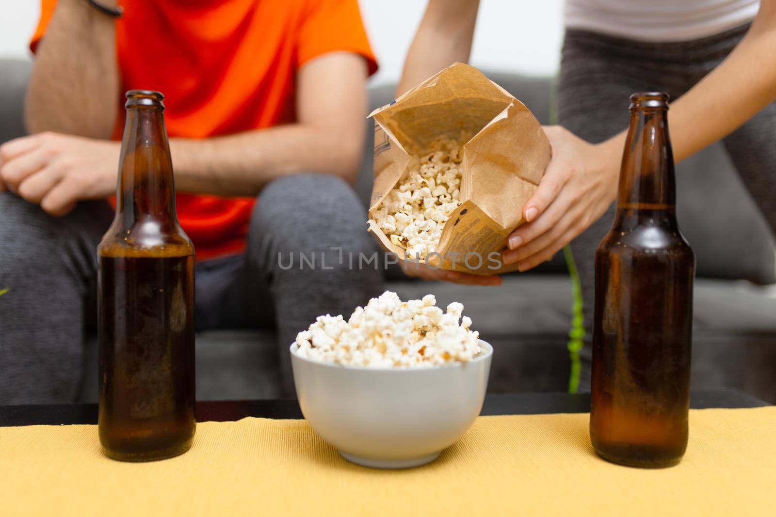 abstract couple watching sports game on tv. girl puts more popcorn
