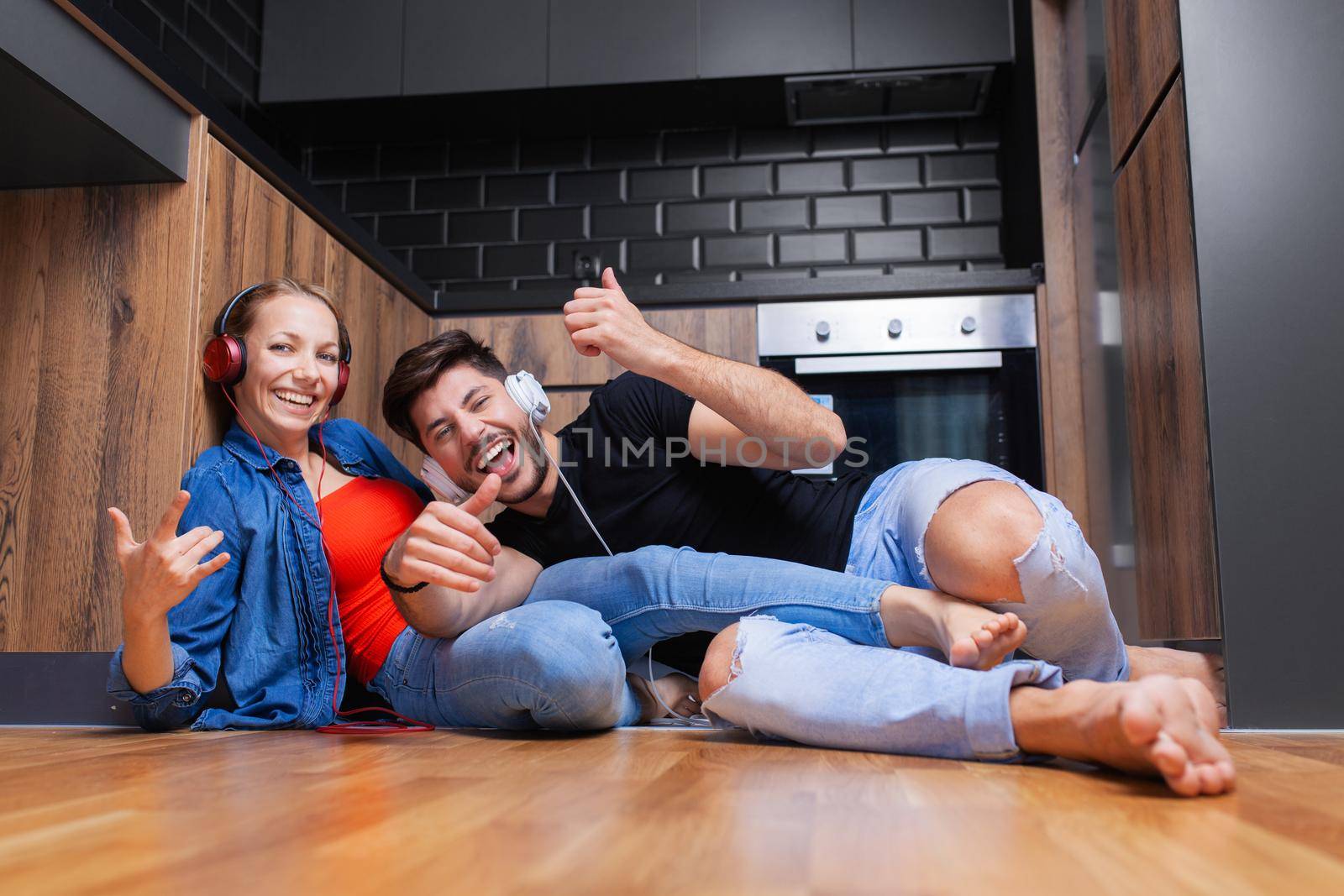 couple fooling aroung on the floor of a modern kitchen by kokimk