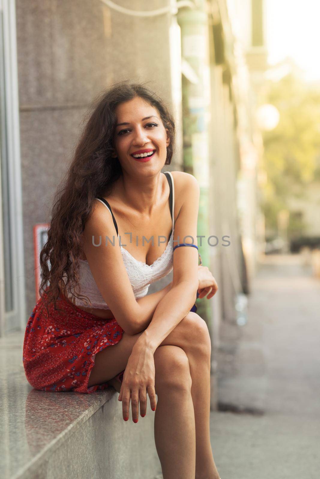 girl sitting on the sidewalk looking at camera