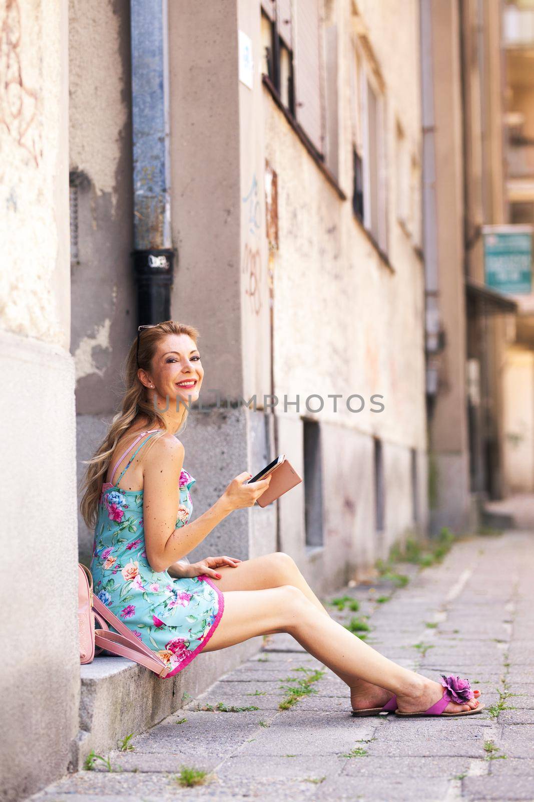 girl sitting on the sidewalk checking her phone by kokimk