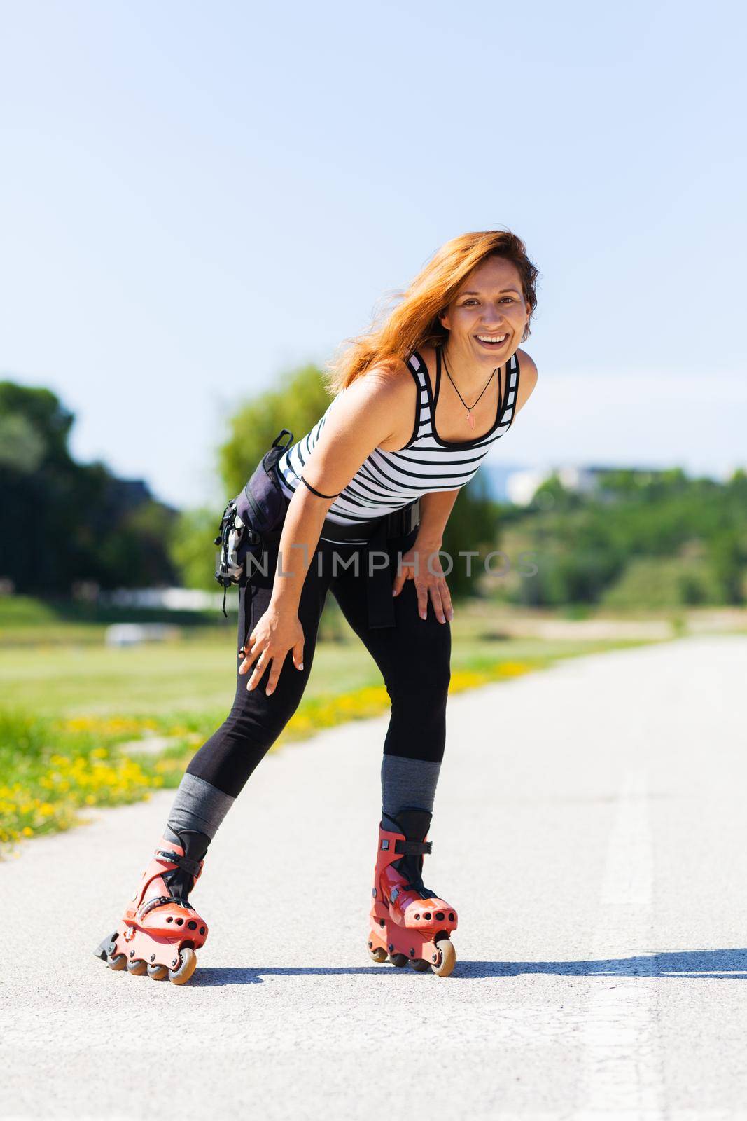 roller skating girl on asphalt road outdoors on a hot summer day