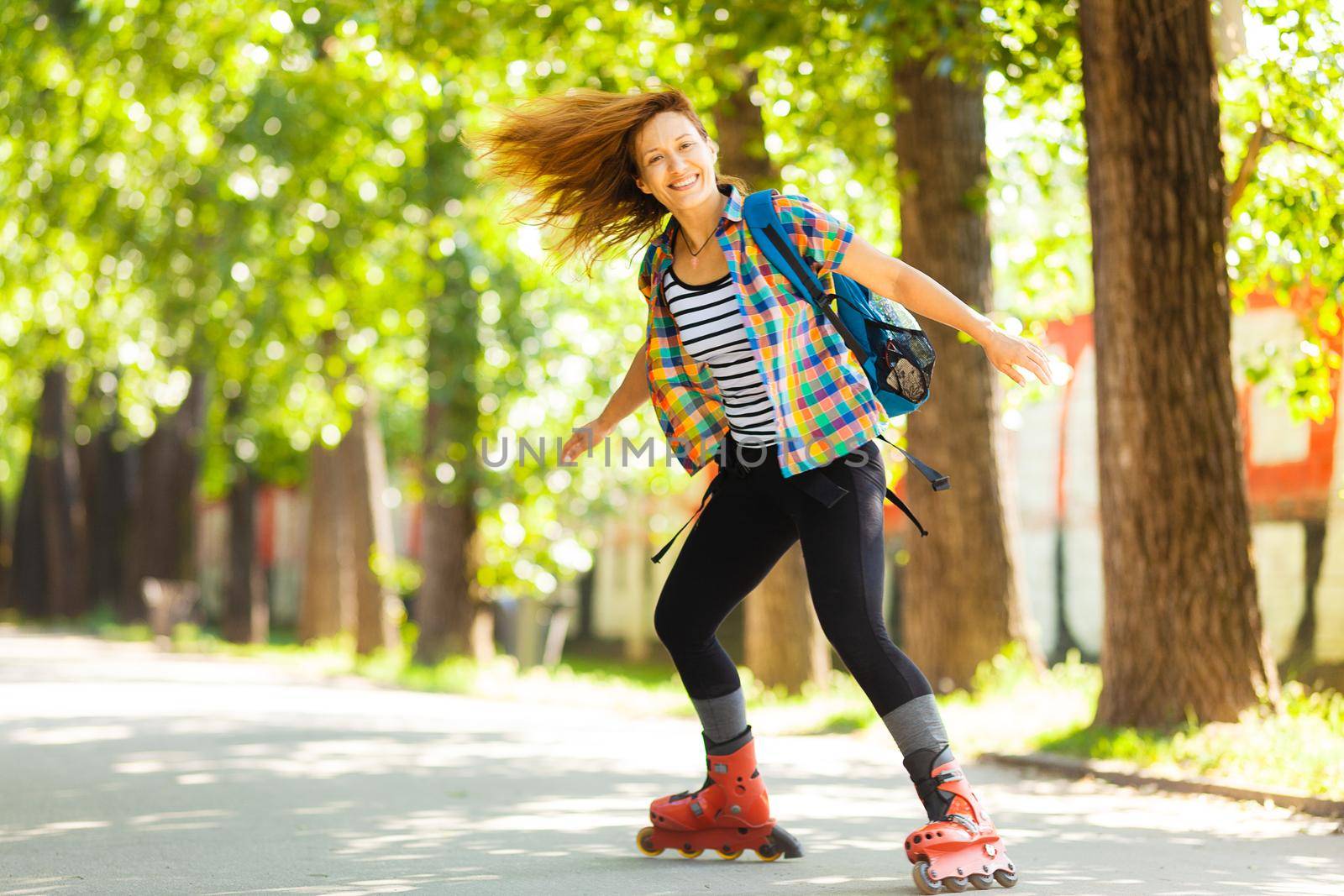 roller skating girl on asphalt road outdoors on a hot summer day