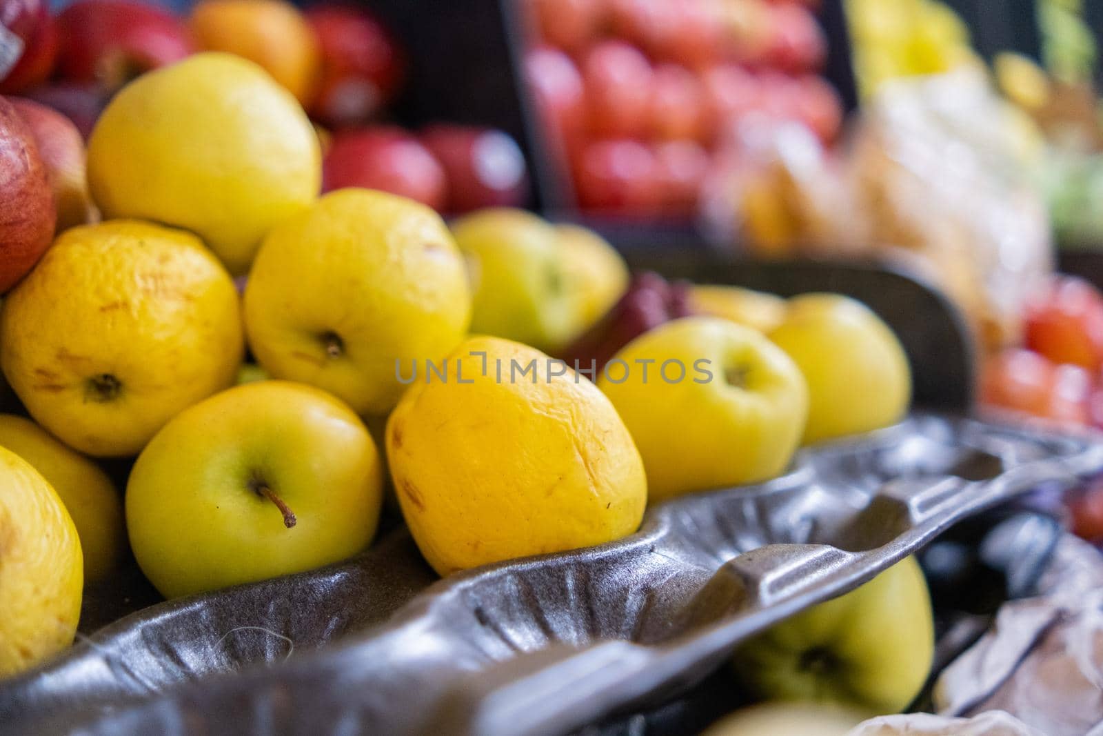Close-up of colorful fruit stand with fresh yellow and red apples, and more. Juicy-looking fruit for sale on stall with blurry background inside classic Mexican market. Healthy food