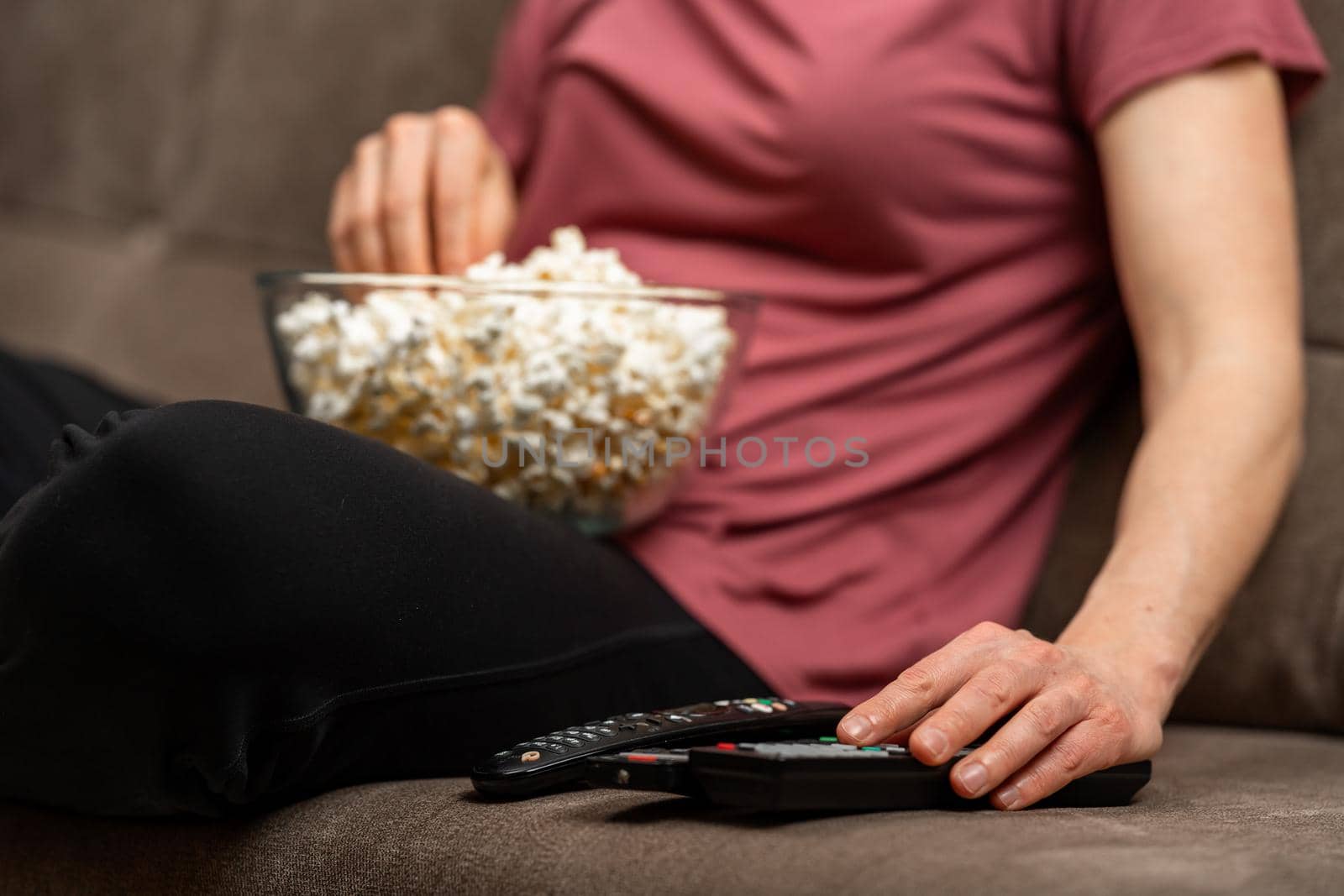 bowl with popcorn while watching a movie on TV. remote control on the sofa.