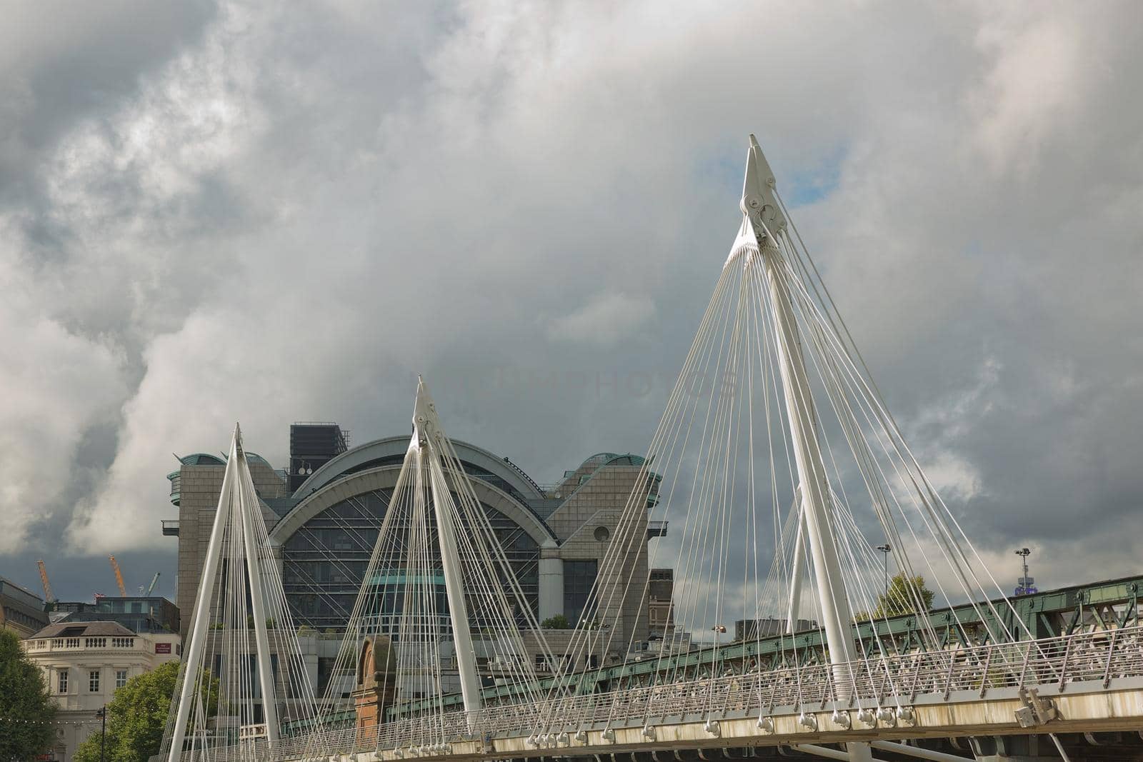 View of the Golden Jubilee Bridges and Charing Cross Station from the South Shore of the River Thames in London on a cloudy Summer day by wondry