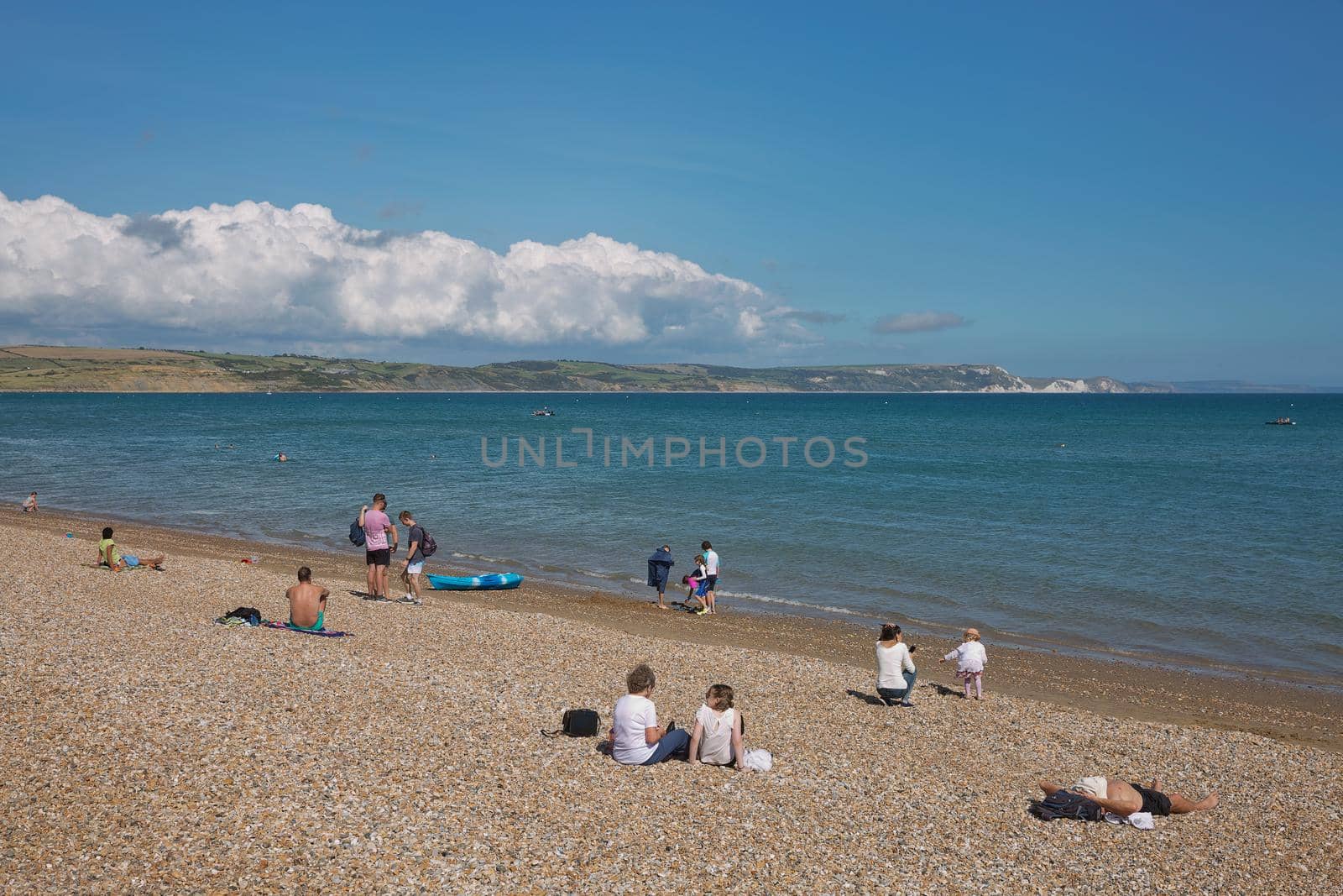 WEYMOUTH, DORSET, ENGLAND, UK - AUGUST 15, 2017: People and tourists enjoying sunny summer day at the beach in Weymouth, Dorset, UK