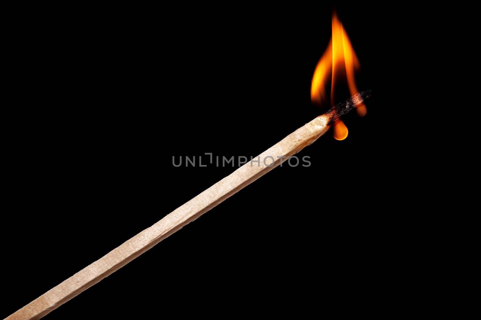 one long match stick burning against black background