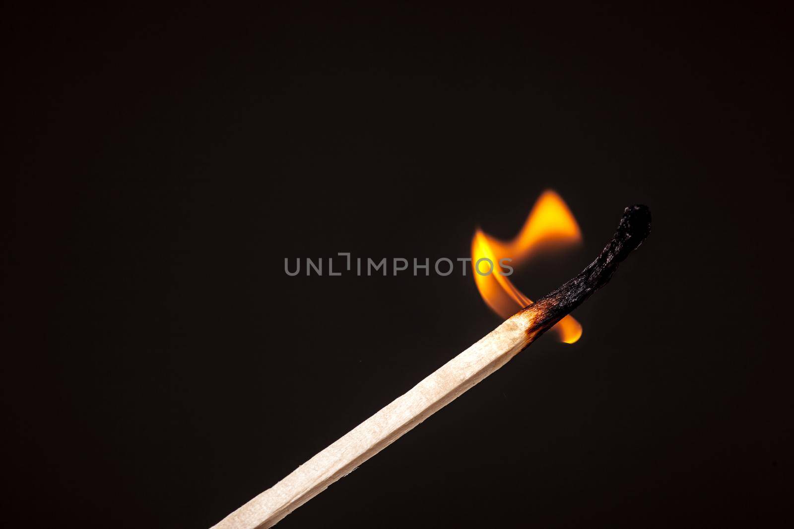 matchstick burning against black by kokimk