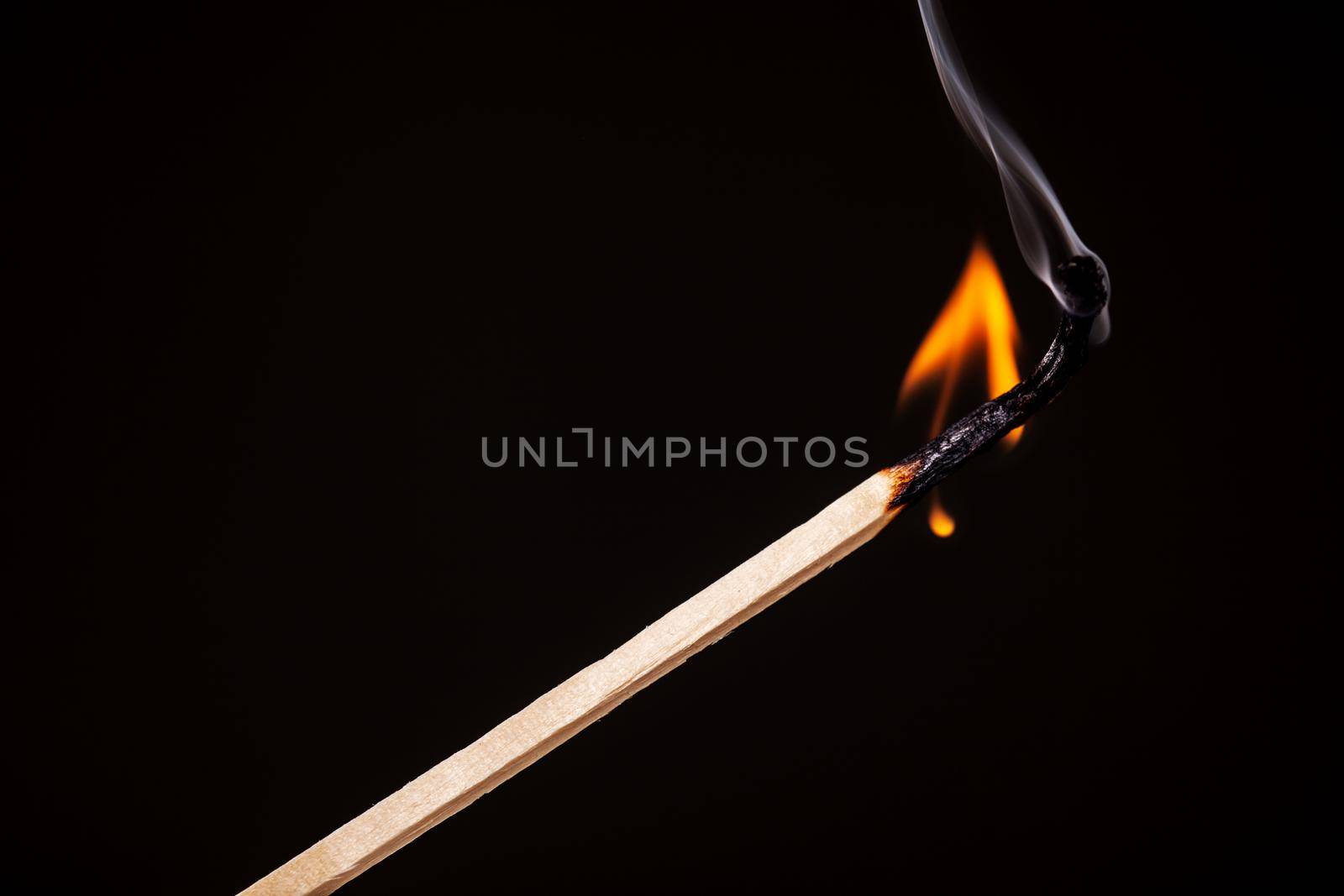 one long match stick burning against black background