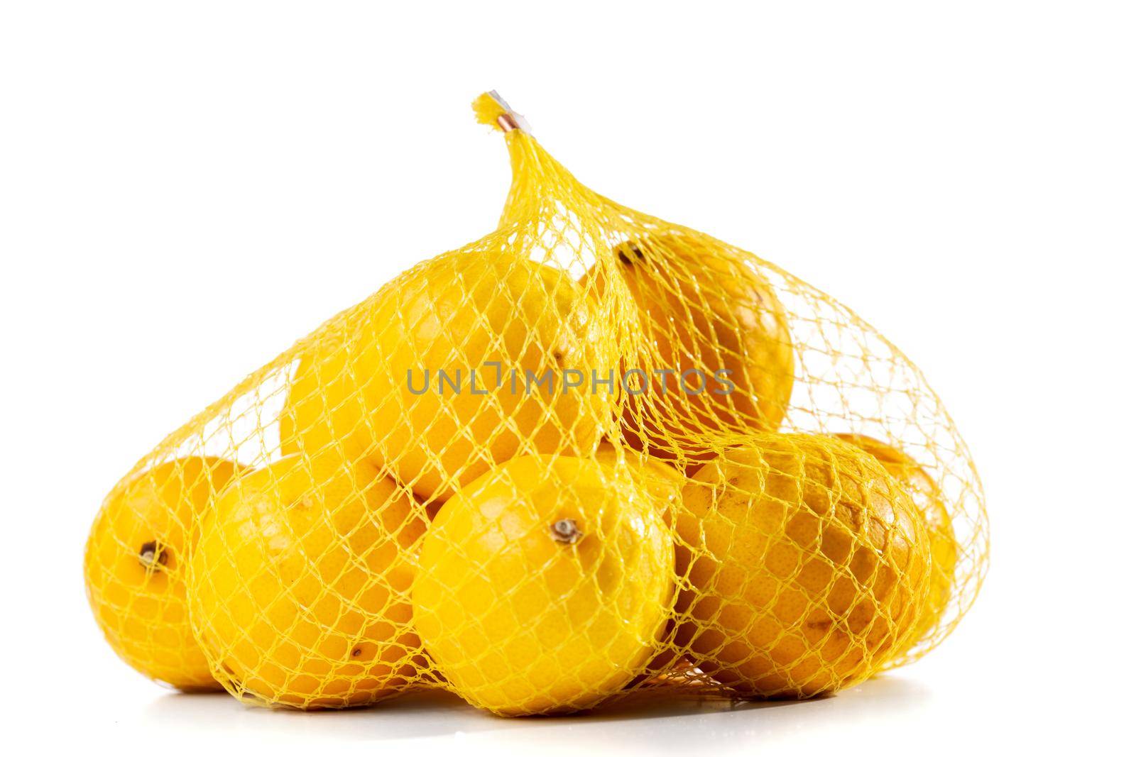 group of ripe lemons in a mesh bag against white background