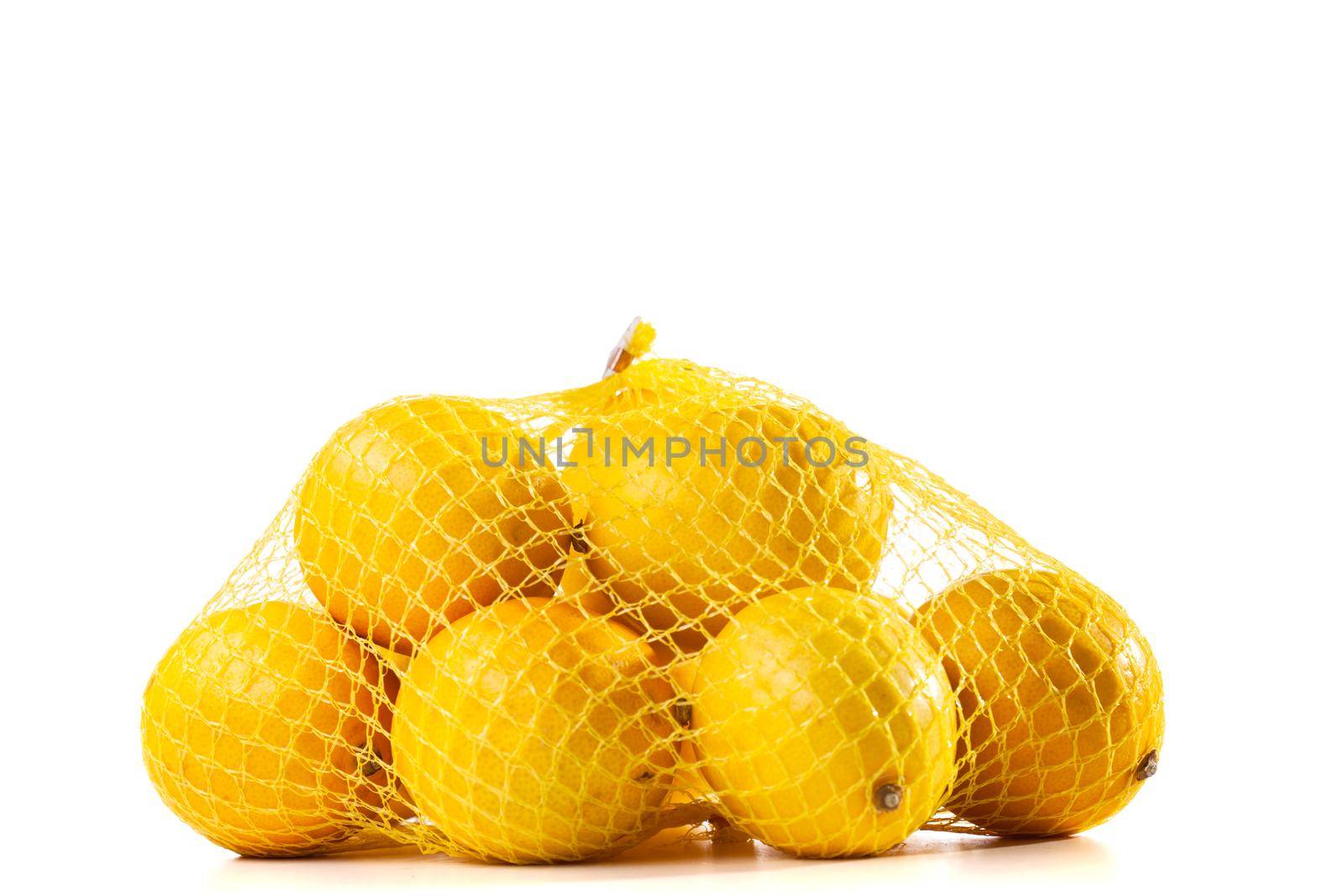 group of ripe lemons in a mesh bag against white background