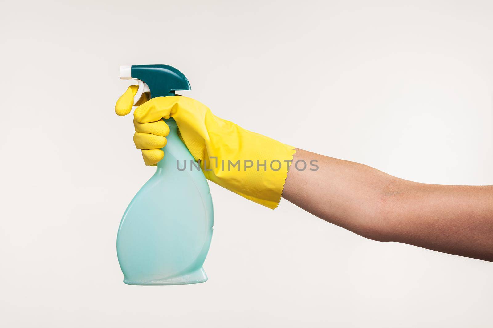 hand in yellow glove spraying liquid cleaning detergent in the air. by kokimk