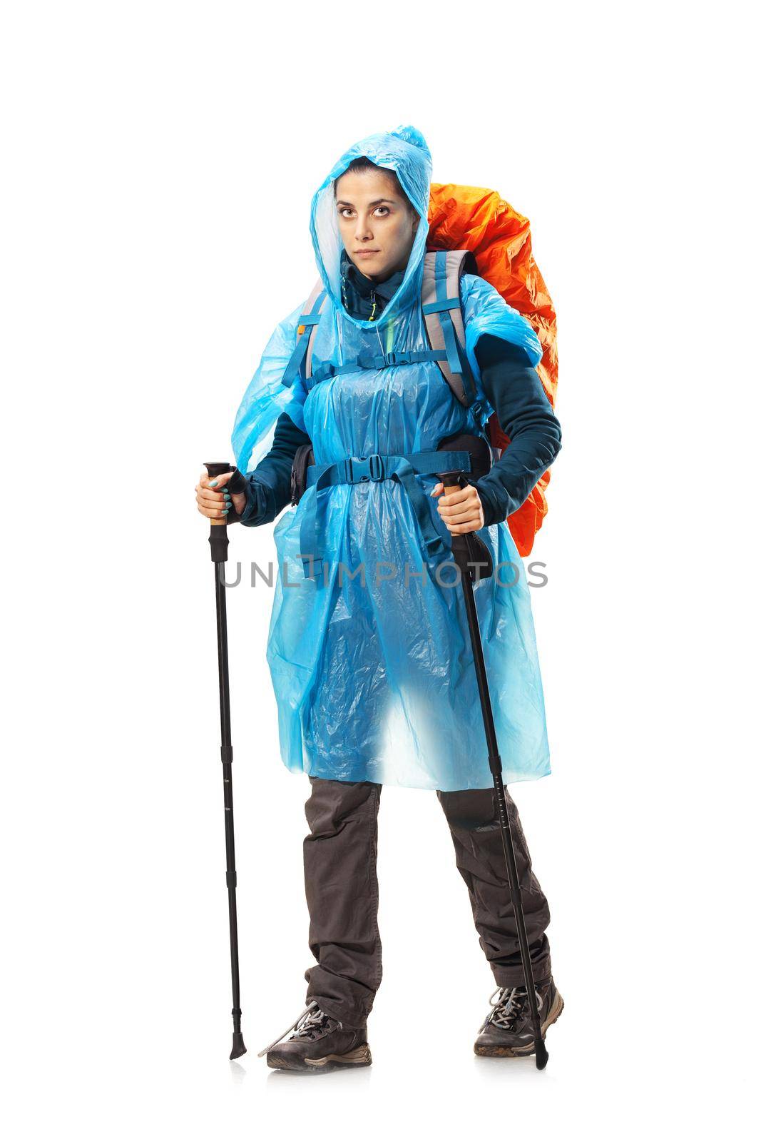 girl with hiking equipment and large backpack, wearing blue raincoat, posing in studio isolated on white by kokimk