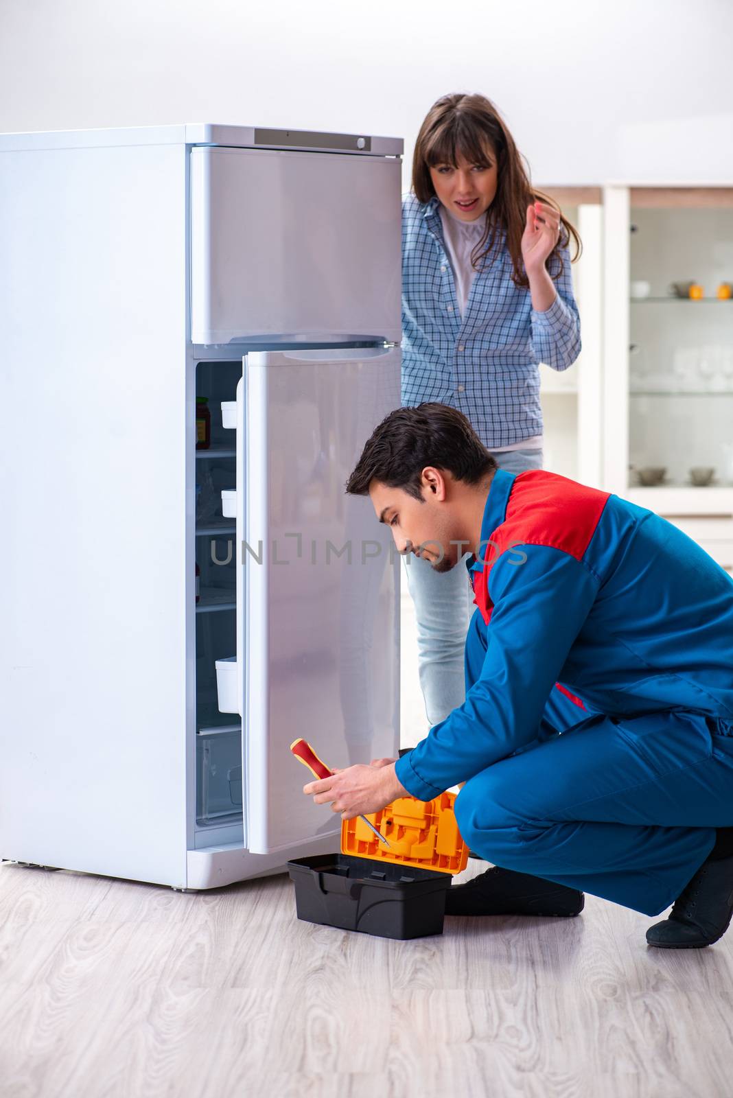 Man repairing fridge with customer