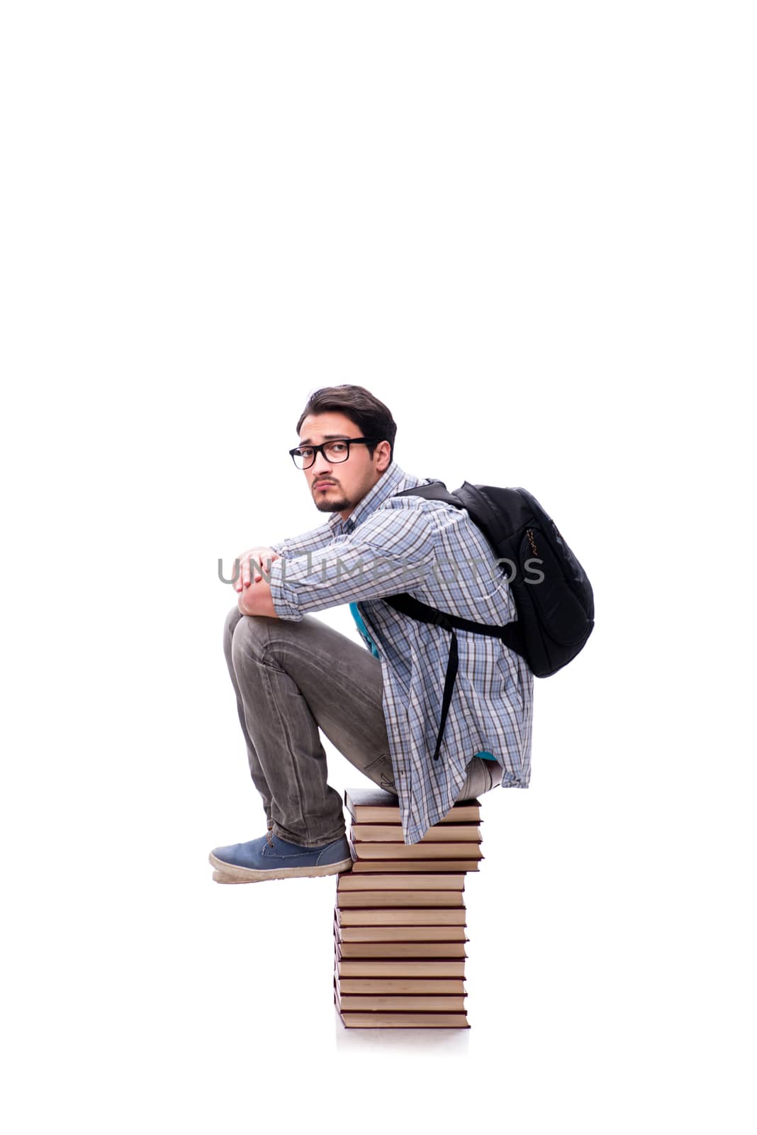 Young student sitting on top of book stack on white