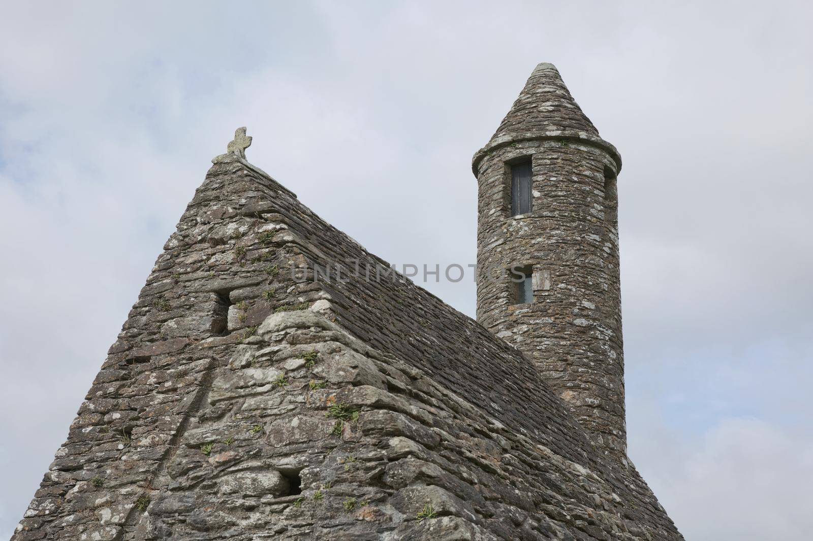Glendalough, co. Wicklow, Ireland - August 10 2019 :Stone round tower and some ruins of a monastic settlement originally built in the 6th century in Glendalough valley, County Wicklow, Ireland.