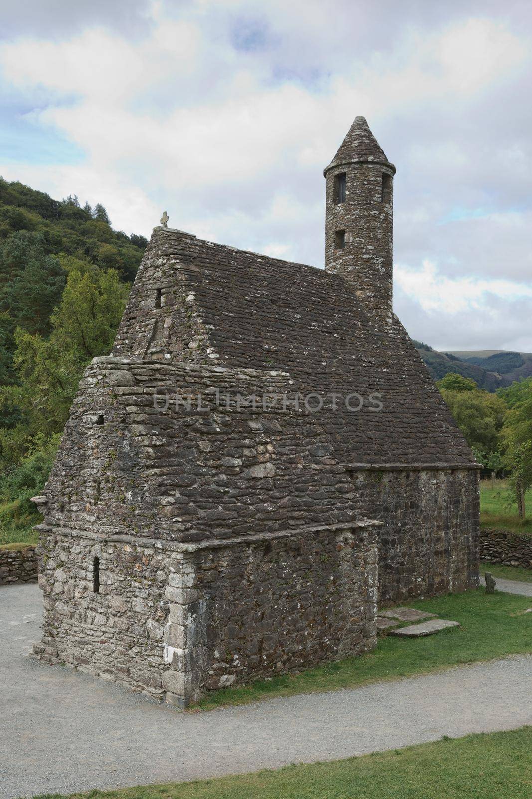 Glendalough, co. Wicklow, Ireland - August 10 2019 :Stone round tower and some ruins of a monastic settlement originally built in the 6th century in Glendalough valley, County Wicklow, Ireland.