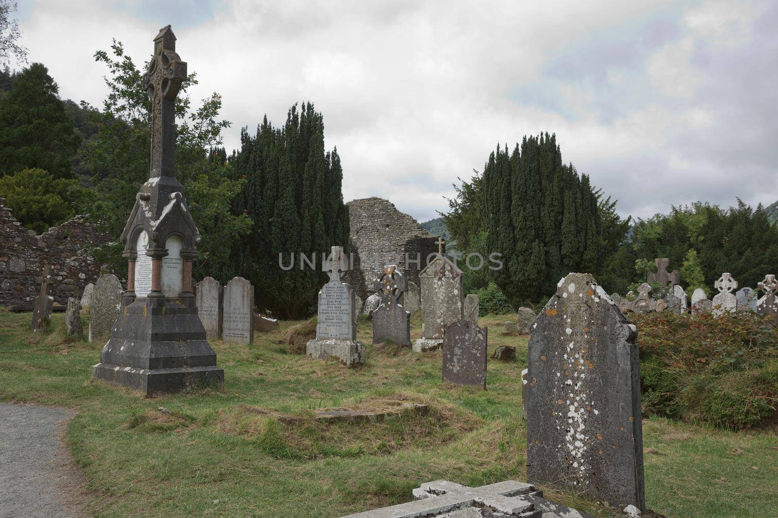 Glendalough, co. Wicklow, Ireland - August 10 2019 :Stone round tower and some ruins of a monastic settlement originally built in the 6th century in Glendalough valley, County Wicklow, Ireland.