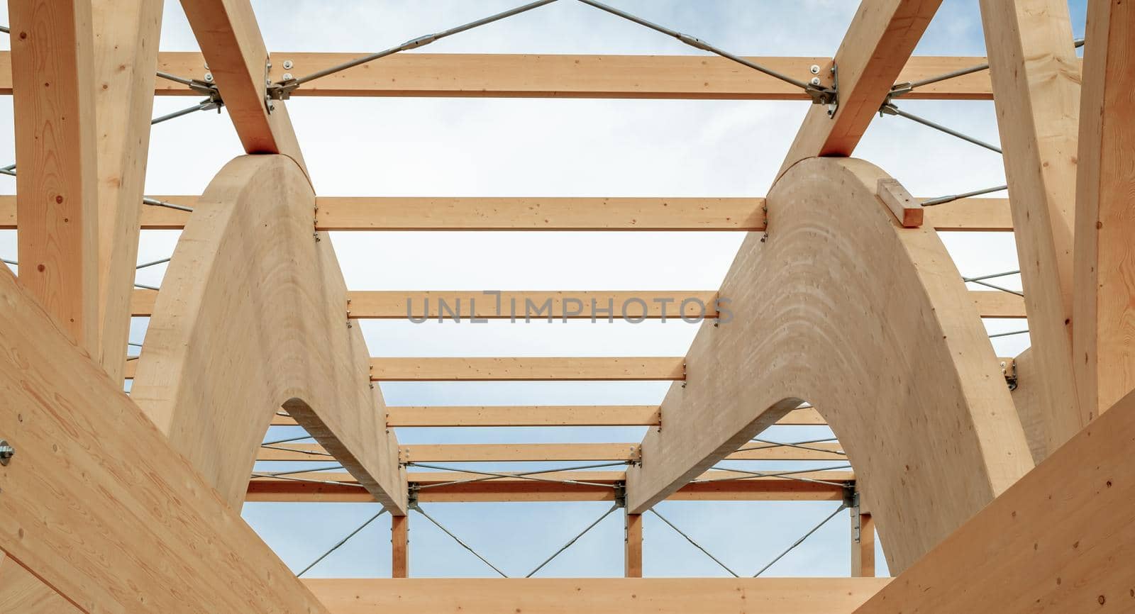 Detail of a modern wooden architecture in glued laminated timber on a blue cloudy sky