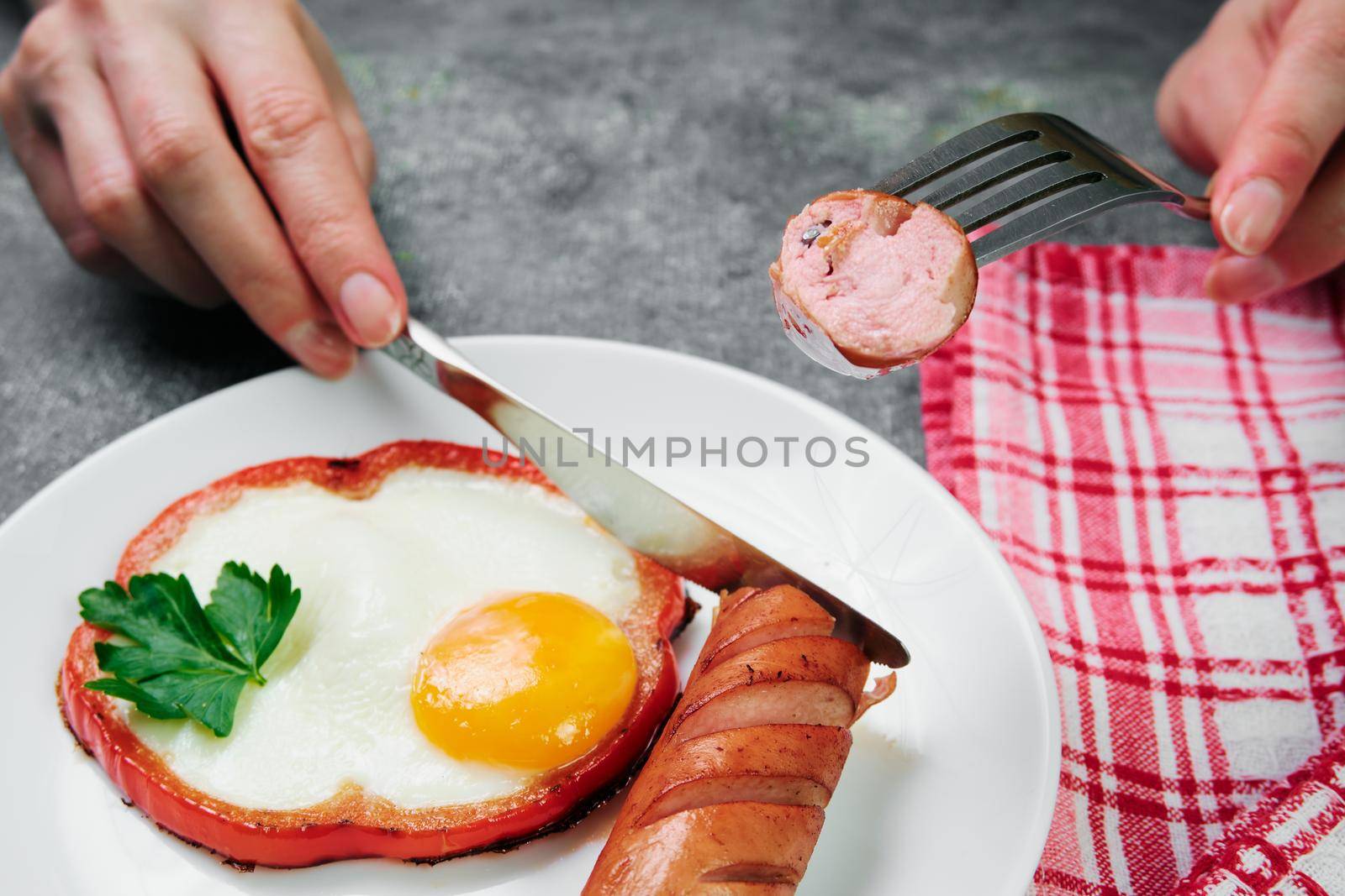 fried egg, red pepper, sausage, towel and cutlery on a dark table