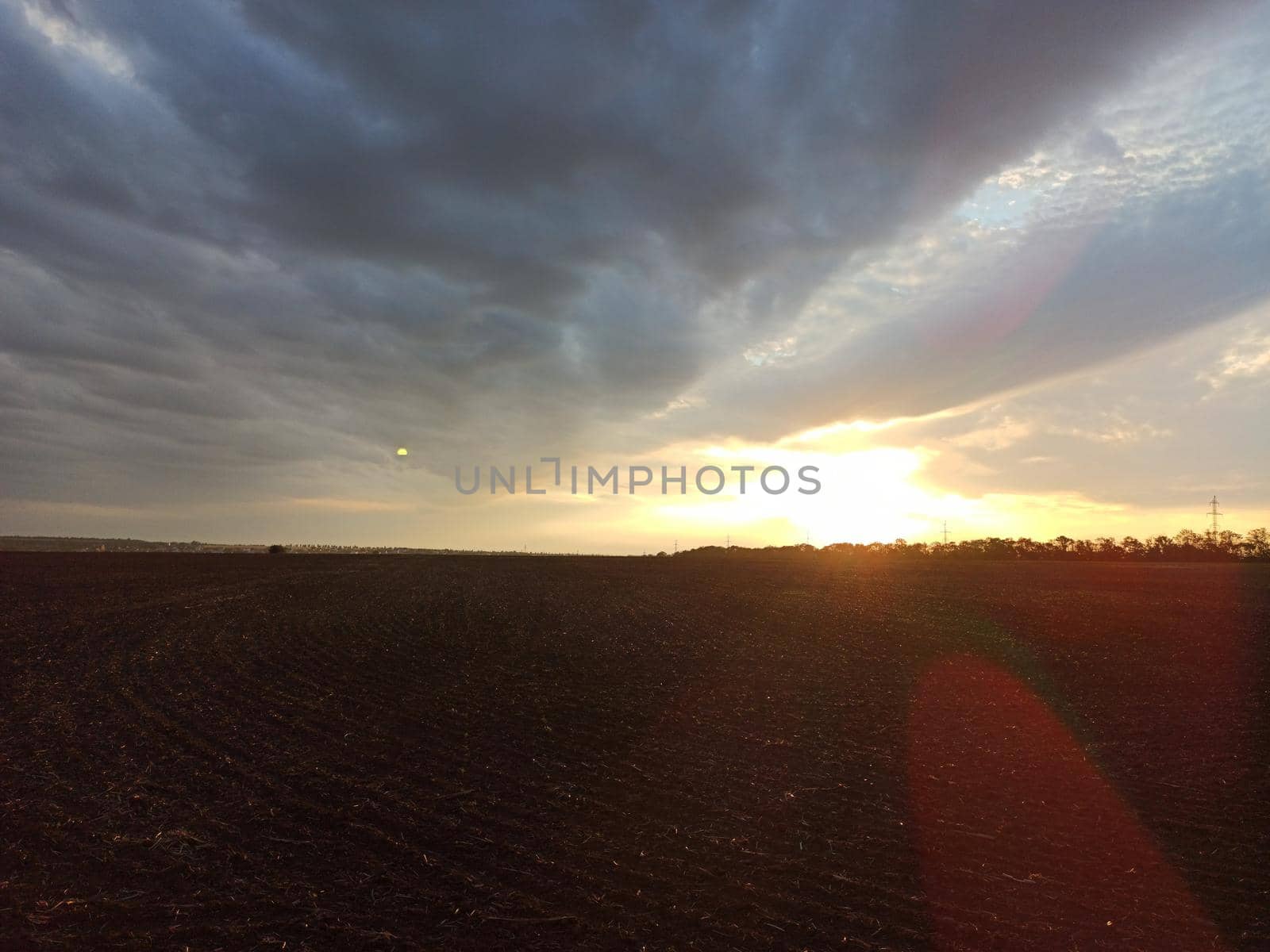 Sunset over a plowed field. Summer evening at summer