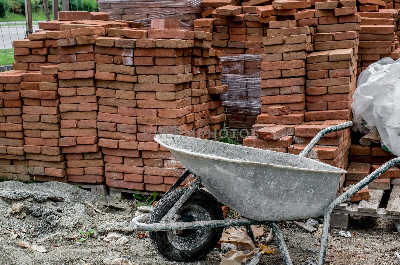 wheelbarrow with abandoned plaster next to a pile of bricks