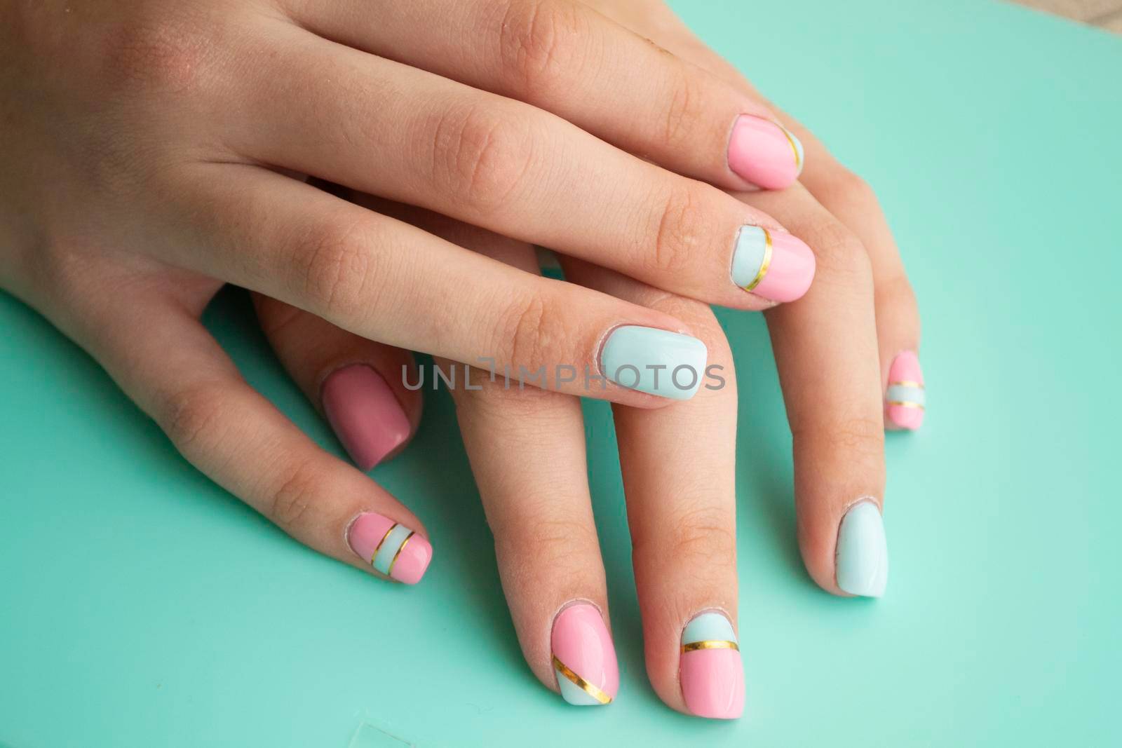 Women s hands with a stylish manicure in teal or blue and pink by annaolgabymonaco