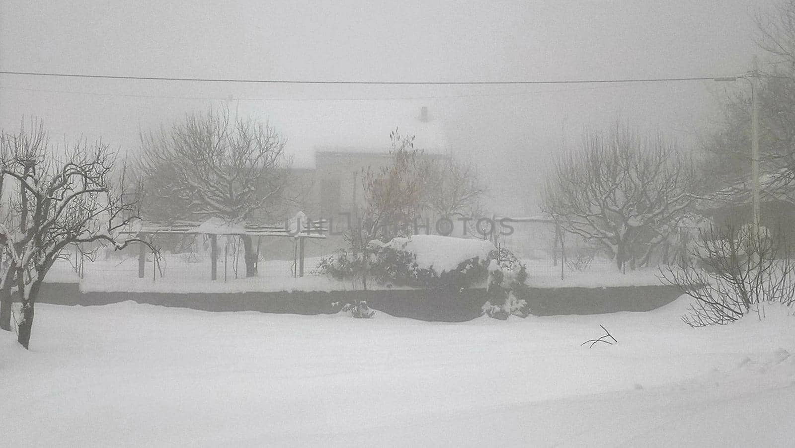 Liguria, Italy - February, 04,2021: Amazing heavy snow from the villlage in Italy. Beautifull photography of the white background with grey and blue sky. Snow and some iced trees.