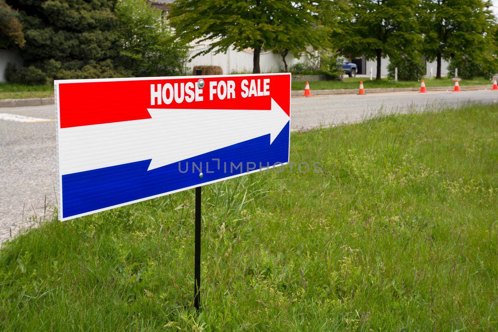 'House for sale' open house directional pointer on green lawn at road turn