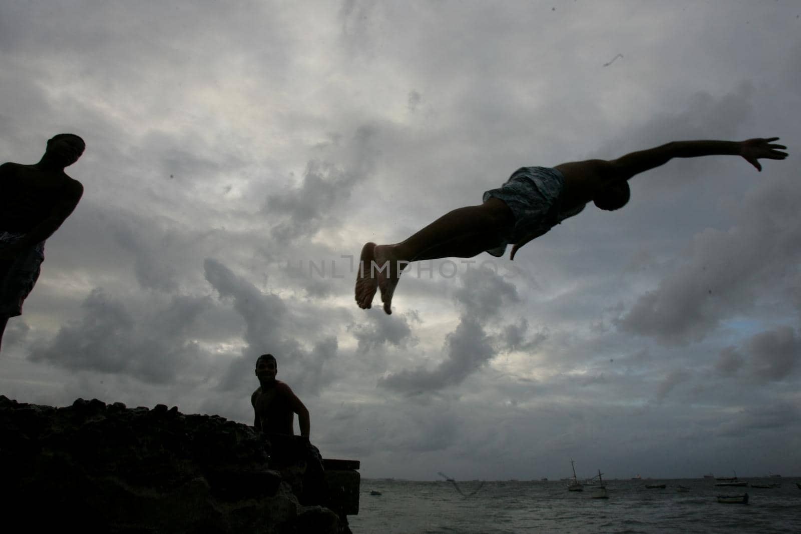 salvador, bahia, brazil - may 10, 2013: Young people jump from the breakwater at Forte de santa Maria, in Porto da Barra in the city of Salvador.
