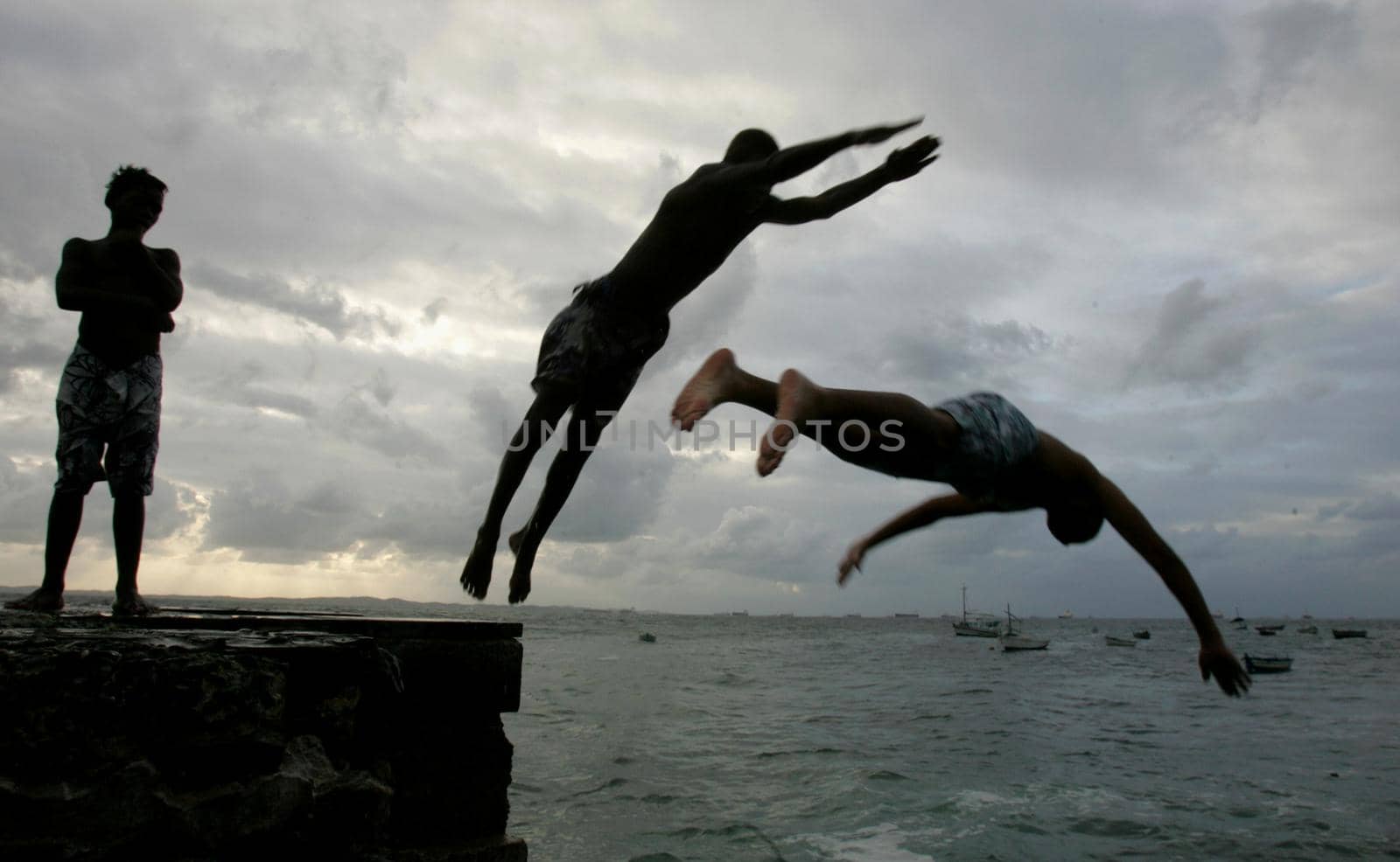 salvador, bahia, brazil - may 10, 2013: Young people jump from the breakwater at Forte de santa Maria, in Porto da Barra in the city of Salvador.