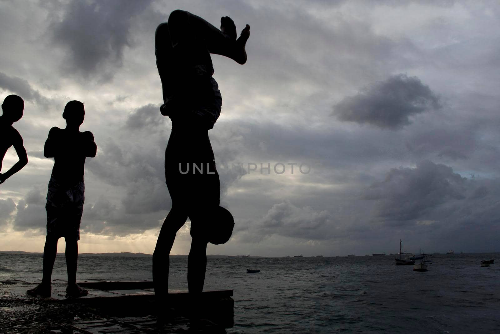 salvador, bahia, brazil - may 10, 2013: Young people jump from the breakwater at Forte de santa Maria, in Porto da Barra in the city of Salvador.