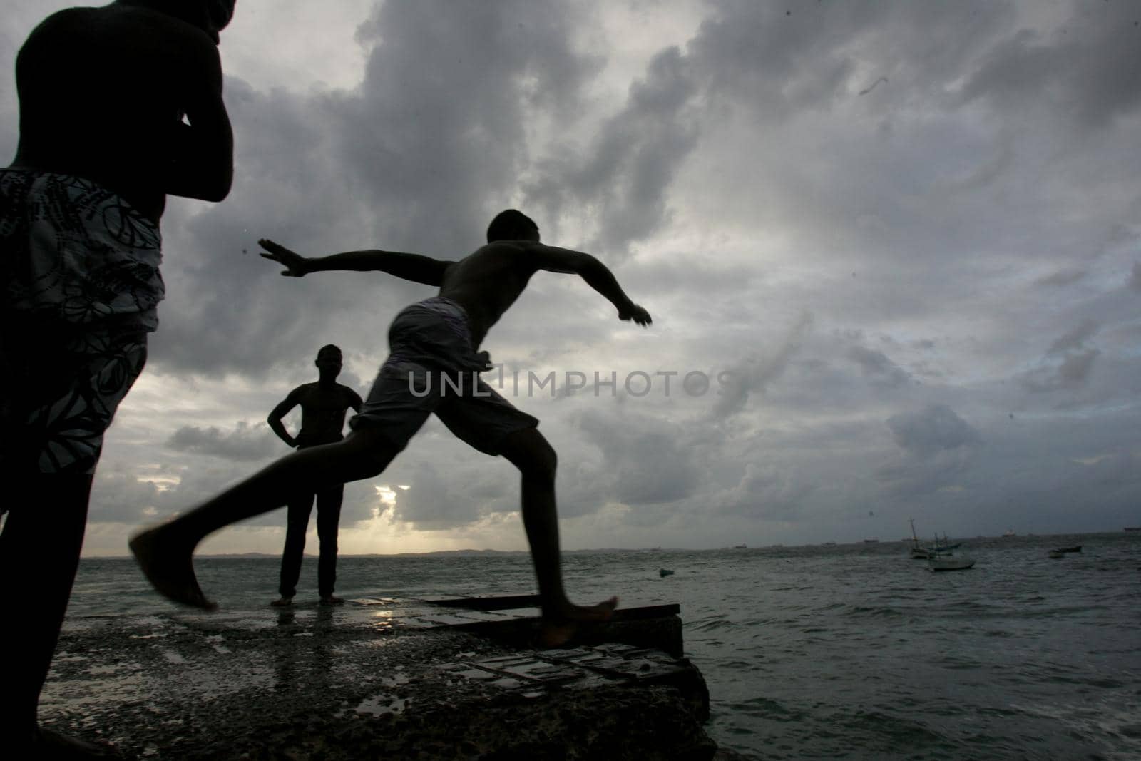 salvador, bahia, brazil - may 10, 2013: Young people jump from the breakwater at Forte de santa Maria, in Porto da Barra in the city of Salvador.
