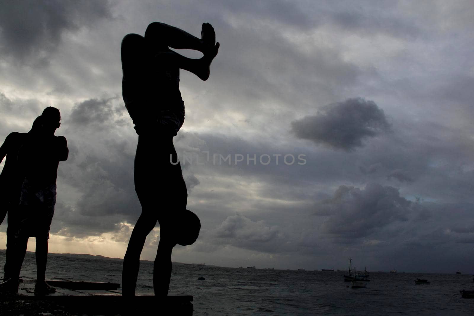 salvador, bahia, brazil - may 10, 2013: Young people jump from the breakwater at Forte de santa Maria, in Porto da Barra in the city of Salvador.