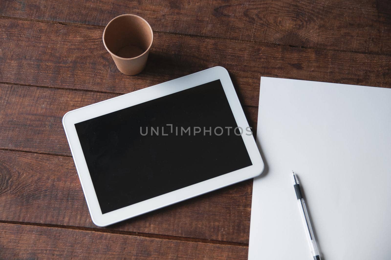 Modern office workplace with tablet pc on the table. On the table there is a tablet and a white sheet of paper with a pen. For a design presentation or portfolio.