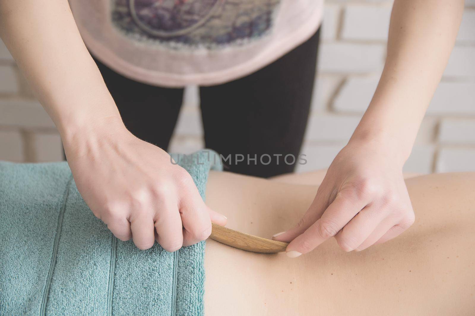 therapeutic back massage in the spa salon makes the girl a massage with wooden knives