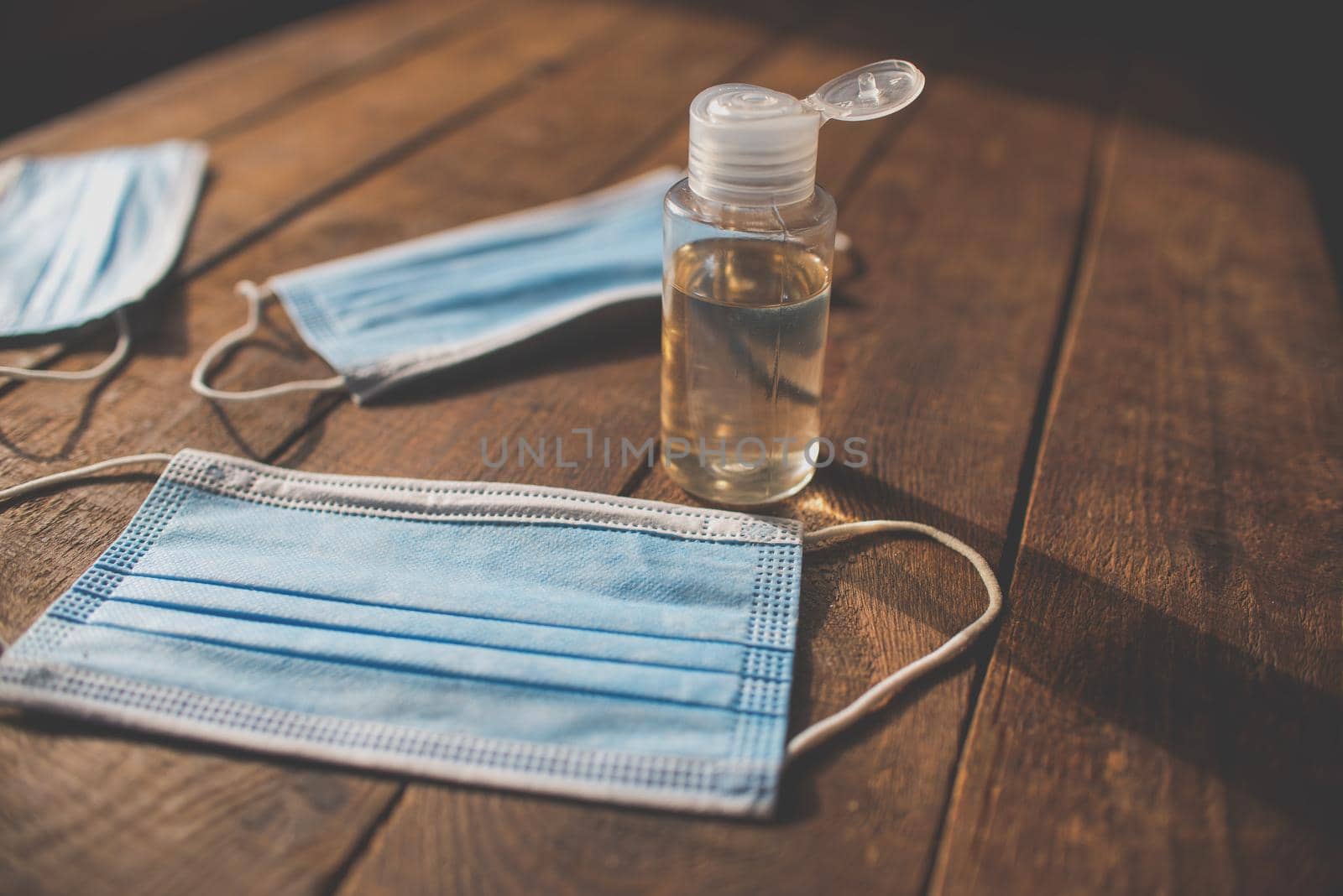 hand sanitizer and disposable masks lie on a wooden table by ozornina