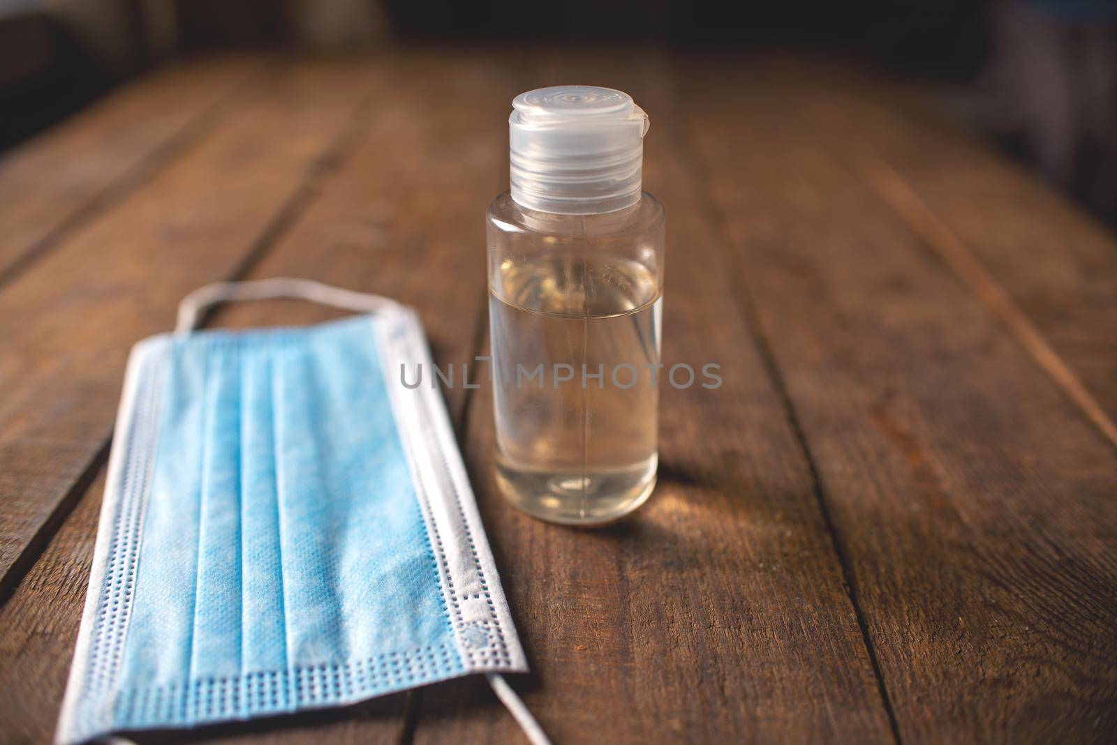 plastic bottle with hand sanitizer and disposable masks lie on a wooden table