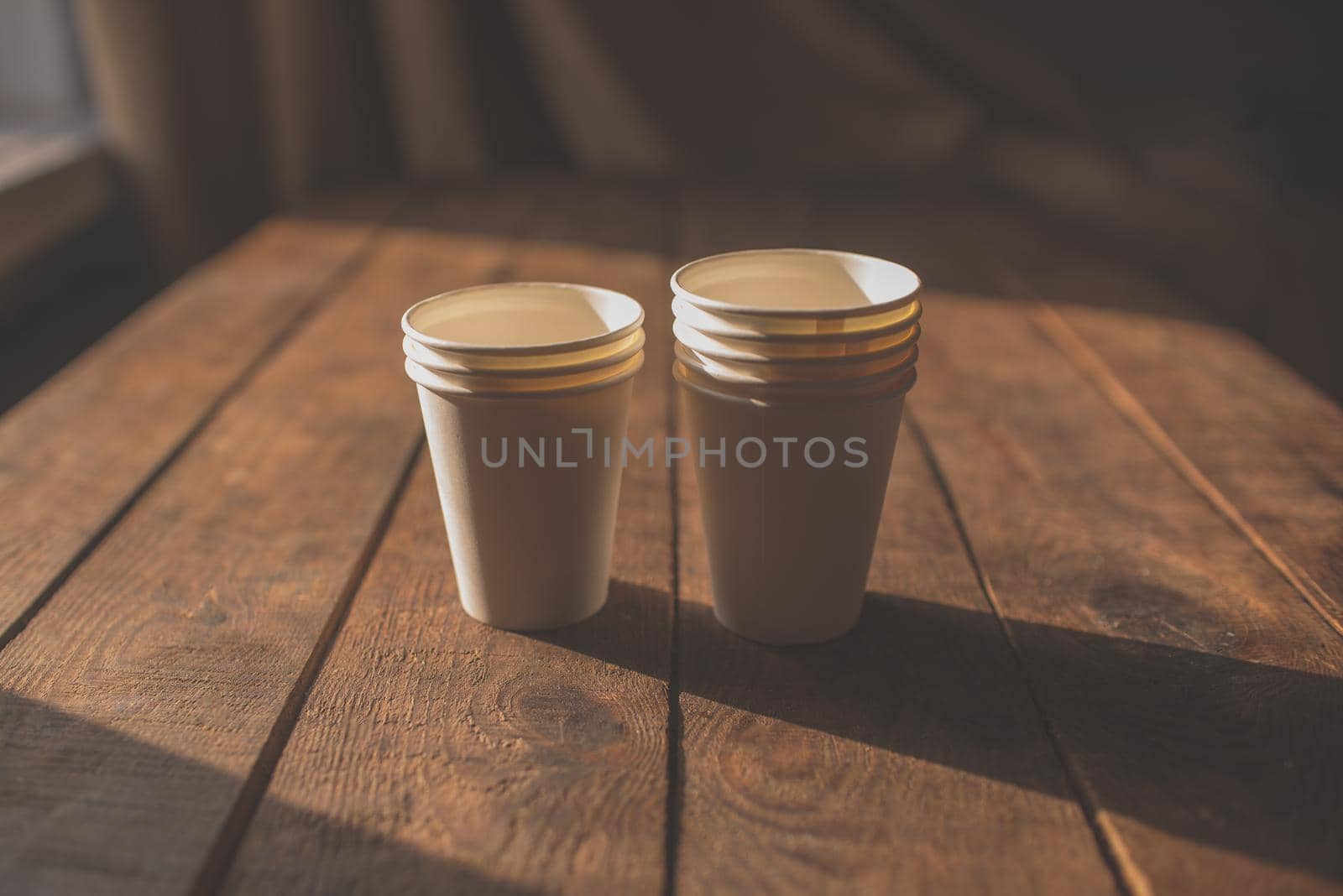 disposable cups made of white kraft paper stand on a wooden table by ozornina