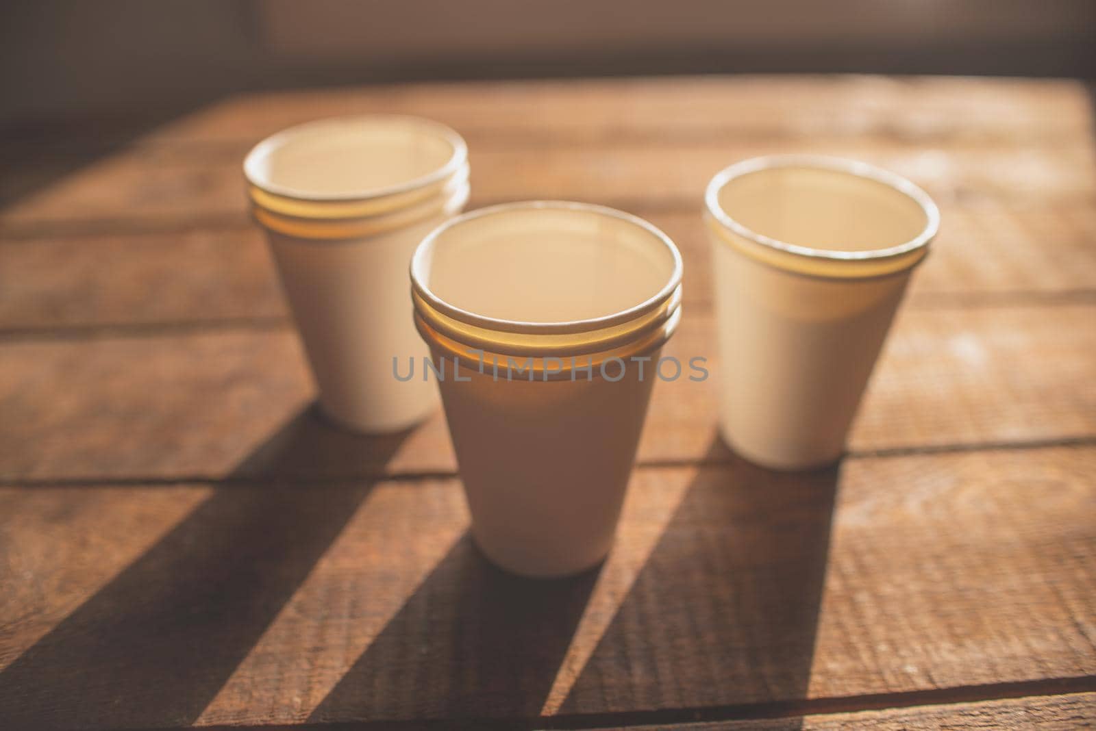 disposable cups made of white kraft paper stand on a wooden table by ozornina