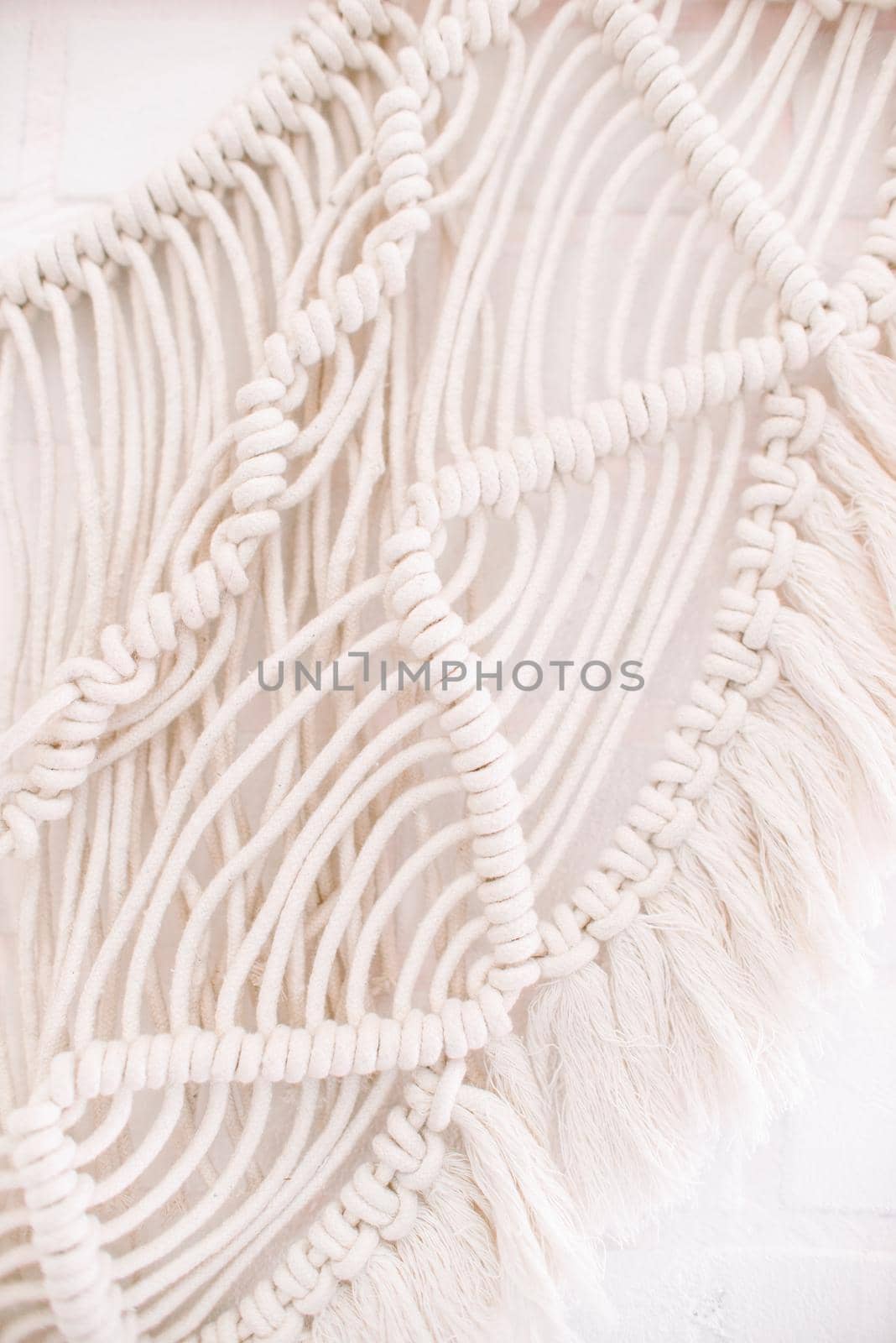 handmade macrame pattern a fragment of a wall panel in the boho style of beige cotton threads of natural color using the technique for home and wedding decor