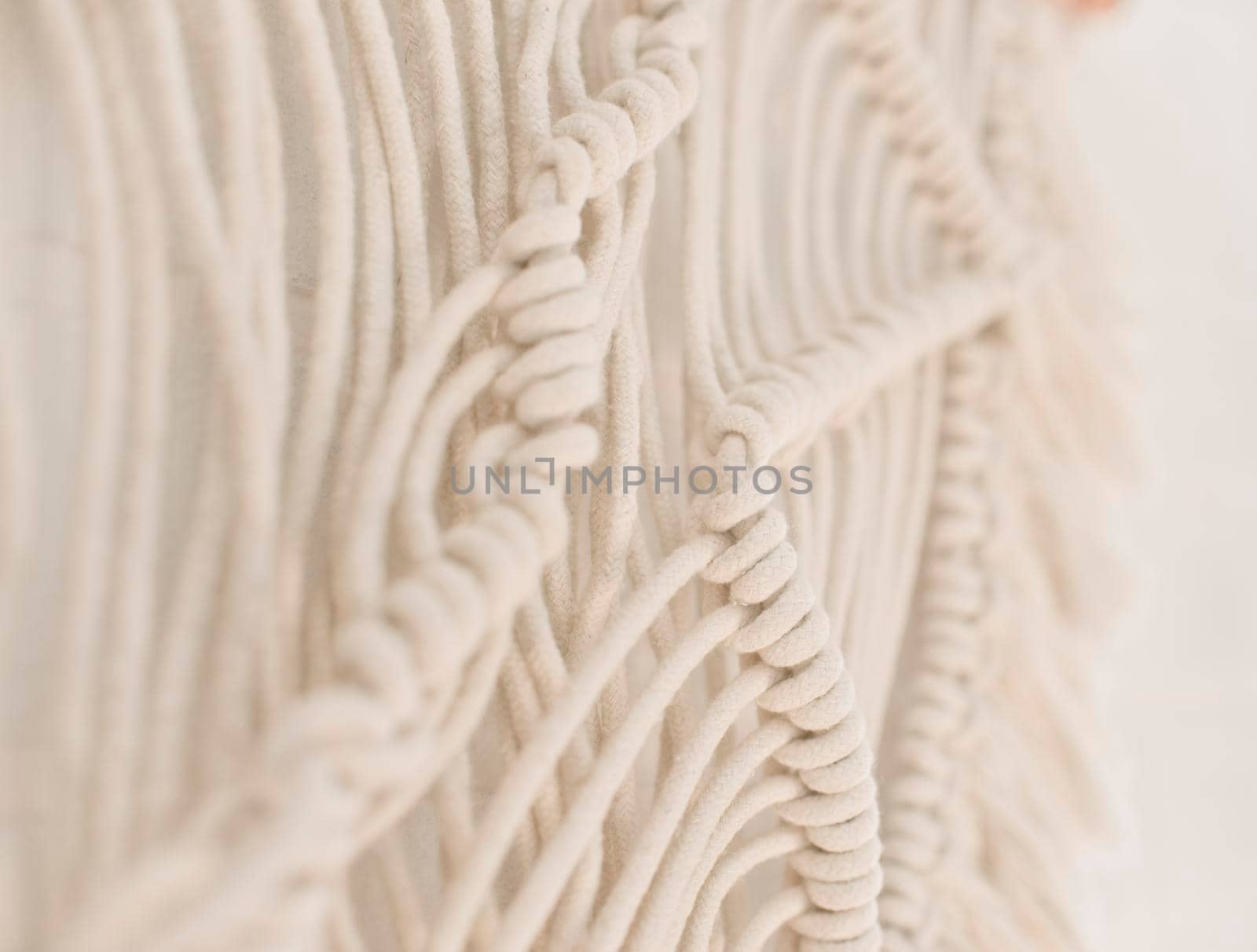 handmade macrame pattern a fragment of a wall panel in the boho style of beige cotton threads of natural color using the technique for home and wedding decor