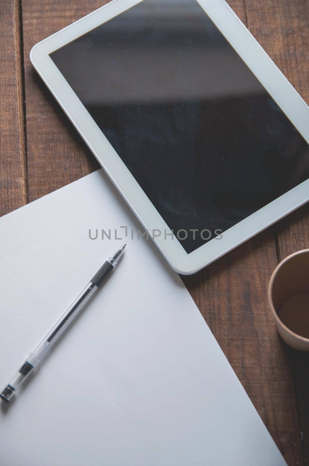 Office workplace with tablet pc on the table. On the table there is a tablet and a white sheet of paper with a pen. by ozornina