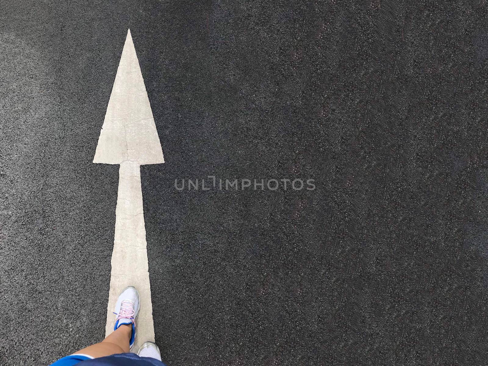Woman sneaker shoe and Arrow on street with copy space background by Yoopho