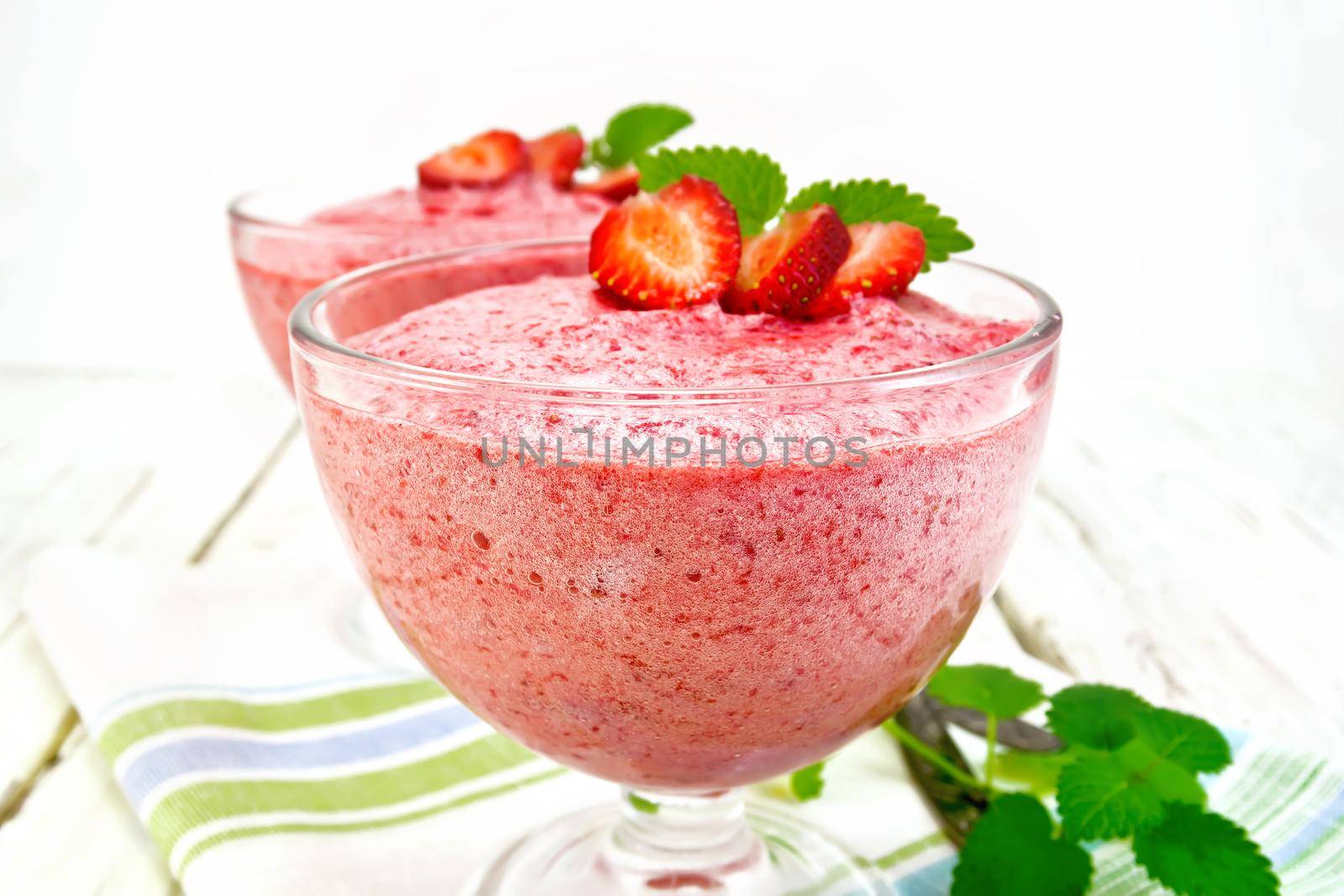 Jelly air strawberry sambuk in two glass bowls, mint on a napkin on a light wooden board background